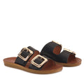 A pair of Los Cabos Womens Dina Black Light Flexible Two Strap Slide Sandals, featuring large gold buckles on brown anatomical footbeds with flat soles for comfortable arch support. The sandals are displayed at a slight angle against a white background.