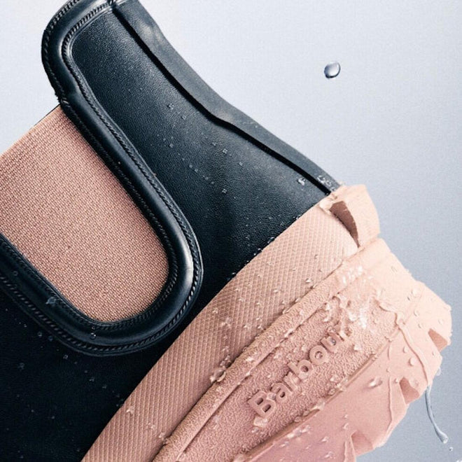 Close-up of Barbour Nimbus Dusky Grey/Gardenia Pink Chelsea Wellingtons—women’s rainboots with waterproof ankle design, black and pink color blocks, glistening water droplets, and Barbour embossed on the Gardenia Pink sole., 5063669171677, 5063669171684, 5063669171691, 5063669171707, 5063669171714, 5063669171721