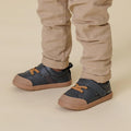 Children's Boston Boston First walking toddlers blue sneaker shoes with brown soles worn with beige pants on a beige background.,
9420075347878,
9420075347861,