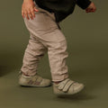 Child wearing beige pants and shoes on a green background.,
9420075347779,
9420075347762,