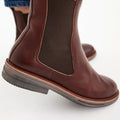 Close-up of a person wearing Rollie Womens Chelsea Rise Vintage Mocha Leather Boot with dark elastic side panels, light brown soles, and a Vibram outsole, standing on a white background., 9339554341682, 9339554341699, 9339554341705, 9339554341712, 9339554341729