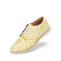 The Rollie Womens Derby Sunshine Splash Leather Shoe features a premium leather upper with a yellow and white abstract leaf pattern, white sole, and lace-up design. Photographed against a plain white background.
