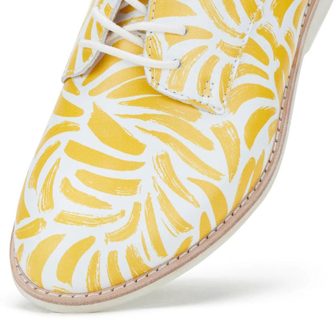 Close-up of the Rollie Womens Derby Sunshine Splash Leather Shoe in white premium leather with yellow abstract brushstrokes, white laces, and light stitching along the sole for sneaker-like comfort., 9781760774783, 9781760774790, 9781760774806, 9781760774813, 9781760774820