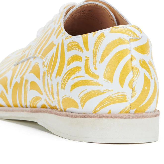 Close-up of the Rollie Womens Derby Sunshine Splash Leather Shoe, featuring a white premium leather upper with yellow abstract brushstroke pattern, a white rubber sole, and combining classic Derby style with modern sneaker-like comfort., 9781760774783, 9781760774790, 9781760774806, 9781760774813, 9781760774820