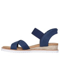 The Skechers Womens Bobs Desert Kiss Golden Lily Navy SLIP IN is a blue open-toe sandal with crisscross fabric and ankle straps, a tan Memory Foam footbed, woven espadrille-style midsole, and white ridged outsole, shown in side profile., 49030, 198739558746, 198739558760, 198739558784, 49034, 49035