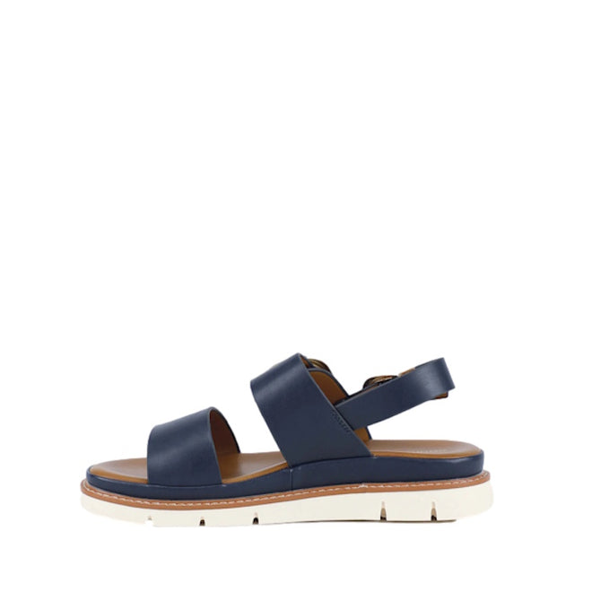 Introducing the Soultbush Garie Navy Blue Women’s Sandal with Back Strap: featuring two wide navy straps, a secure ankle strap with a buckle, a tan cushioned footbed, and a thick white sole with subtle grooves—perfect sandals for effortless coastal living.