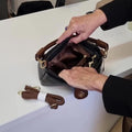 Person opening a Sassy Duck Trinity brown handbag on a white surface.,
44734,
44735,
44736,