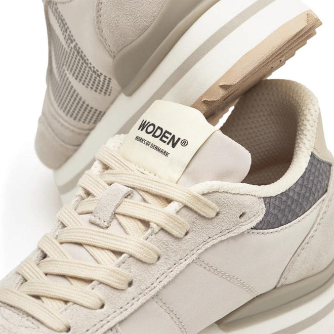 A close-up of Woden Ronja Plateau Delpin Lace Up Sneakers in beige and gray, highlighting laces, side panels, fish leather heel accents, and a “WODEN - HOUSE OF DENMARK” brand label on the tongue., 5713326692365, 5713326692372, 5713326692389, 5713326692396, 5713326692402