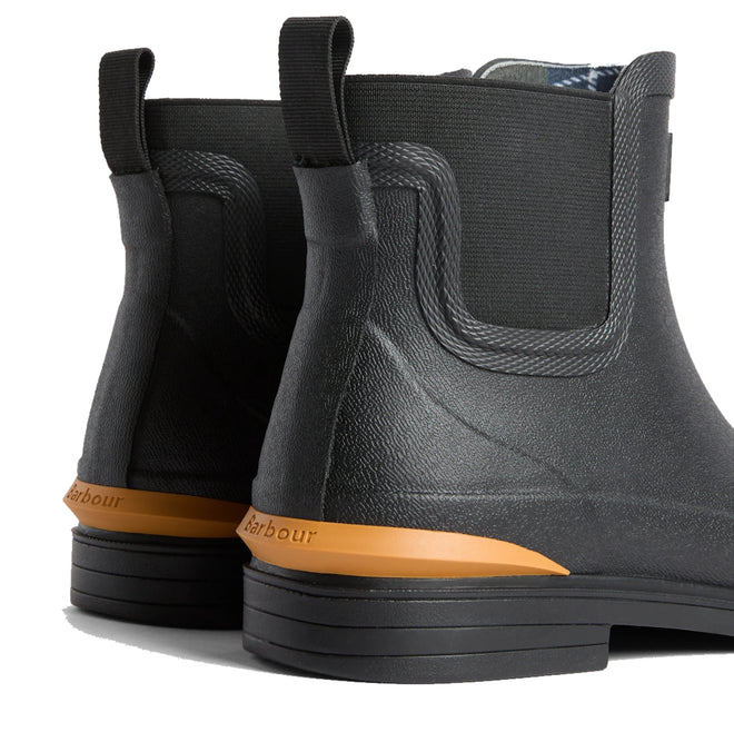 Close-up of the heels of Barbour Abbeyfield Packable Ankle Wellingtons Black, featuring textured surfaces, elastic side panels, and an orange branding detail above the sole—lightweight ankle boots ideal for festivals or wet weather., 54323, 5063669380451, 5063669380468, 5063669380475, 5063669380482, 5063669380499, 54329