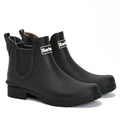The Barbour Wilton Black Chelsea Wellingtons Womens Rainboot features elastic sides, pull tabs, rugged soles, and a tartan lining, shown against a white background.
