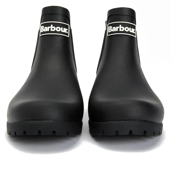 The Barbour Wilton Black Chelsea Wellingtons Women's Rainboot features a chunky sole, white Barbour logo on the shaft, and a classic tartan lining for added style—shown here from the front., 190375411423, 190375411546, 190375411614, 190375411768, 190375411850, 190375412024
