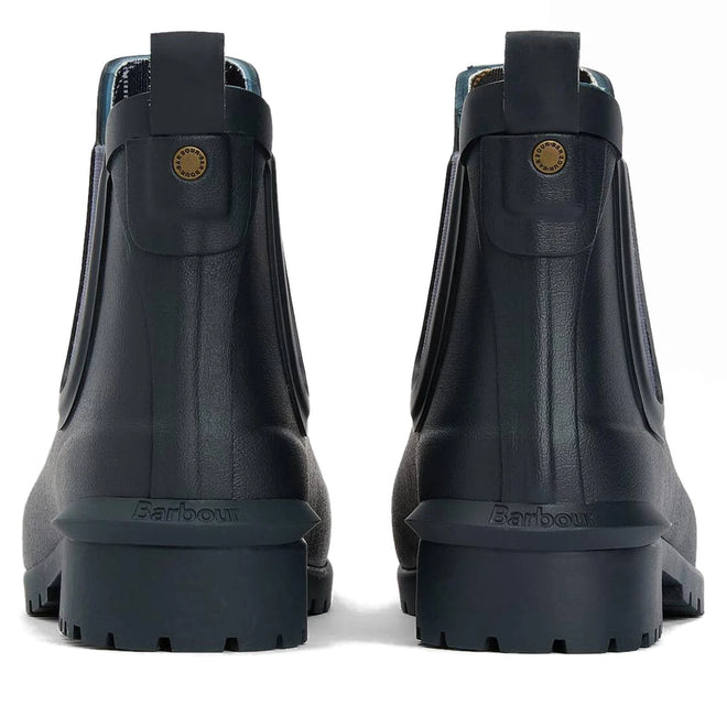 The Barbour Wilton Navy Chelsea Wellingtons Womens Rainboot is shown from the back, featuring thick ridged soles, pull tabs, a small round brass logo on each boot, classic Chelsea-style details, and signature tartan lining., 190375411744, 190375411867, 190375412055, 190375412123, 190375412222, 51392