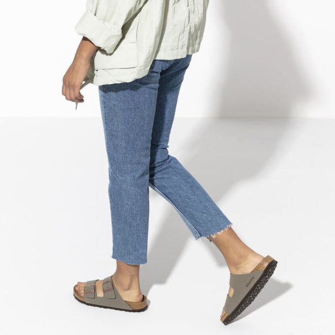 Back view of a women taking a step wearing a pair of stone birkenstock arizona sandals. 4013871744986,4013871744993,4013871745006,4013871745013,4013871745020,4013871745037,,,,,,,
