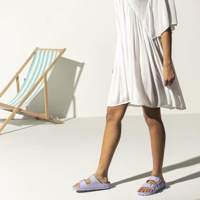 Person wearing light purple sandals with a white dress and deck chair in the background, 
4043734967047,
4043734967085,
4043734967122,
4043734967160,