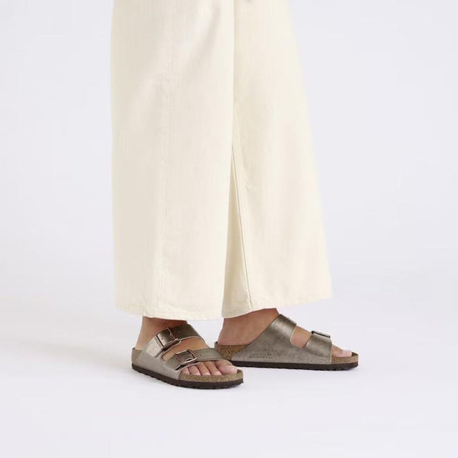 Person wearing Birkenstock arizona graceful taupe metallic sandals with light-colored pants on a white background.,
4067707034901,
4067707034949,
4067707034987,