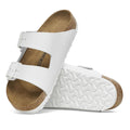 a pair of Birkenstock Arizona Smooth (Pebbled) Leather White Regular Width with double straps, one over the foot and one over the toes with buckle adjustment. Staps are linked at the sides of the foot. Leather thick straps and a suede leather footbed,