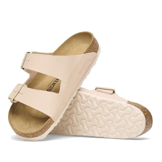 Pair of beige brokenstock slides sandals with cork sole and mono coloured buckles on a white background