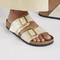 White sandals with gold buckles worn by a person on a white background,
4067707031474,
4067707031511,
4067707031559,