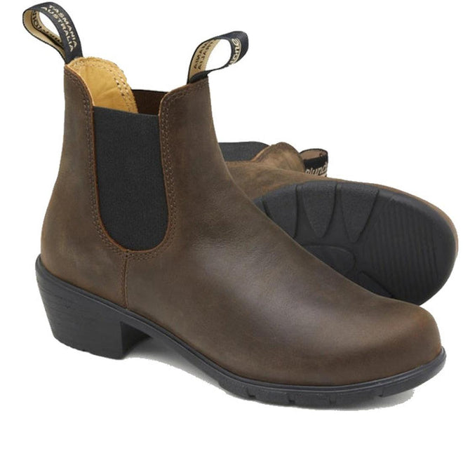 A pair of Blundstone Womens 1673 Heeled Brown Ankle Comfy Boots with black elastic side panels, front and back pull tabs, and low block heels—one stands upright, the other lies on its side.