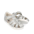 The Bobux Iwalk IW Tropicana II Metallic Silver Sandal 638320 features a woven front, white soles, Velcro strap, and side ventilation—perfect summer shoes for kids.