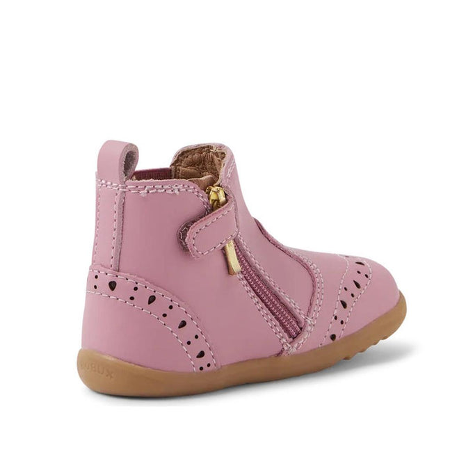 The Bobux Step Up Billie Girls Boot in Lilas Pink features decorative perforations, a brown rubber sole, and a gold side zipper. Displayed at an angle to show the side and back, it's ideal for toddlers taking their first steps., 9420068543560,
9420068543577,
9420068543584,
