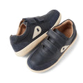 The Bobux Toddlers IWalk IW Champ Sneaker Navy 650509 features navy leather, beige soles and side accents, two hook-and-loop straps, perforated toe details, and the BOBUX logo on the heel.