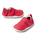 The Bobux Explorer Go Radiant Raspberry First Walker Crawler features small, bright red leather shoes with white soles, Velcro straps, a flexible sole, and textured toe areas for extra grip, displayed on a white background.