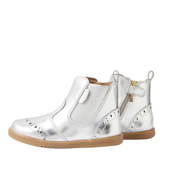 The Bobux IW Iwalk Billie Jodhpur Girls Leather Boot in silver features shiny leather, flexible soles, side zippers, elastic panels, and decorative perforations. One boot is shown facing forward; the other displays its side profile., 9420074856302, 9420074856319, 9420074856326, 9420074856333, 9420074856340