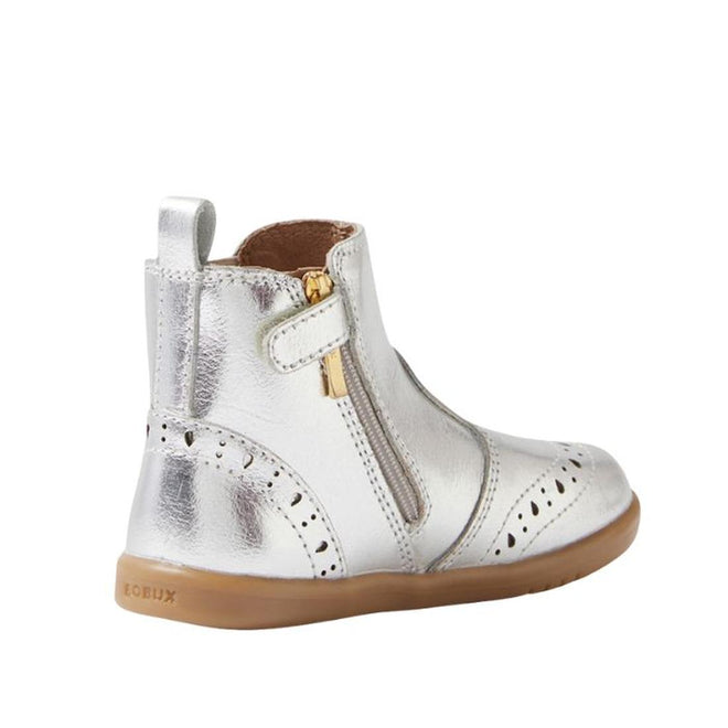 The Bobux IW Iwalk Billie Jodhpur Girls Leather Boot in silver features a shiny leather upper, tan flexible sole, side zipper, decorative perforations, and heel pull tab. This toddler boot is shown from the side., 9420074856302, 9420074856319, 9420074856326, 9420074856333, 9420074856340