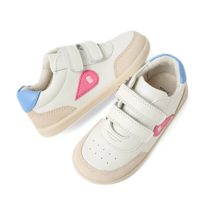 The Bobux IW Iwalk Toddlers Champ Leather Sneaker in White Pink features white leather uppers, beige soles, pink heart designs on the sides, blue heel accents, and two hook-and-loop straps per shoe, shown against a white background.