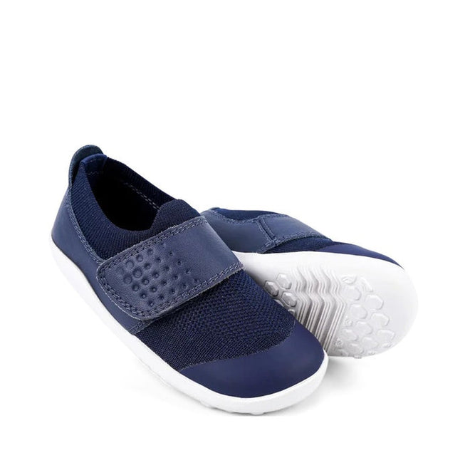 The Bobux Iwalk Lo Dimension III Blue Navy Trainer 638506 Unisex features navy uppers with a honeycomb pattern, white soles, and a textured Velcro strap. One shoe stands upright while the other is tilted to display the sole., 9420062025925, 9420071311699, 9420068531536, 9420071311712, 9420068531550