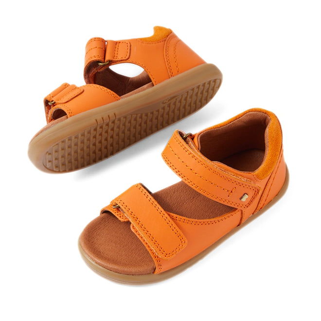 Two Bobux IWalk Driftwood Sandal Orange Peel open-toe leather sandals for toddler boys are displayed: one upright and the other on its side to showcase the light brown, textured rubber sole. These sandals feature adjustable Velcro straps and are designed to offer comfort and breathability, making them ideal for active little ones., 9420074807656, 9420074807663, 9420074807670, 9420074807687, 9420074807694