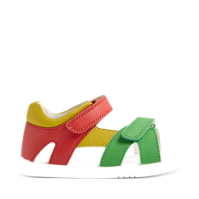 The Bobux IWalk Dune Toddlers Sandal in Grenadine Red features red, yellow, and green leather straps with a white sole and adjustable closures for a secure fit. Shown from the side on a white background, these open-toe sandals combine vibrant style with practical comfort—perfect for adventurous little explorers., 9420074855091, 9420074855107, 9420074855114, 9420074855121, 9420074855138