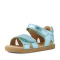The Bobux IWalk Flora Toddlers Sandal in Jelly Mint Metallic Blue features an open toe, charming flower print, adjustable velcro straps, and a flat tan rubber sole. Shown on a white background, these sandals combine comfort and style for playful little ones.