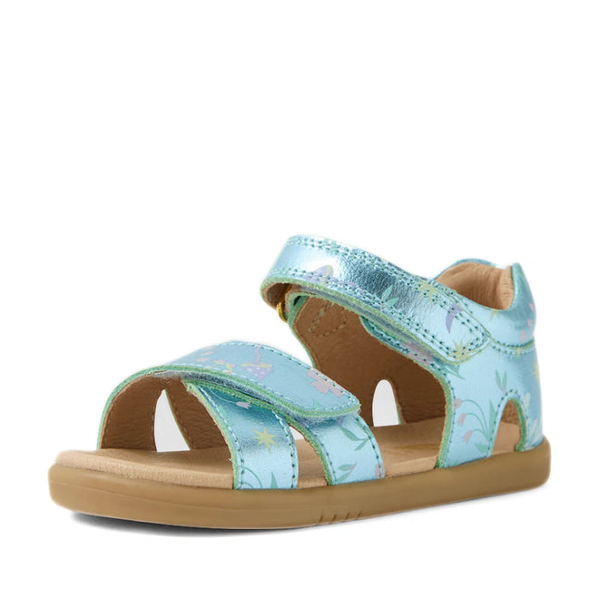 The Bobux IWalk Flora Toddlers Sandal in Jelly Mint Metallic Blue features an open toe, charming flower print, adjustable velcro straps, and a flat tan rubber sole. Shown on a white background, these sandals combine comfort and style for playful little ones.