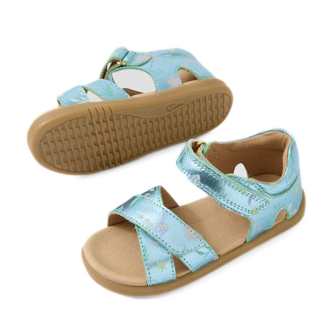 Two Bobux IWalk Flora Toddlers Sandal Jelly Mint Metallic Blue Open Toe sandals for children feature light blue straps, pastel star and rainbow patterns, tan footbeds, and rubber outsoles. One sandal is upright while the other is flipped to display the sole—charming metallic blue sandals perfect for any little one’s adventures.