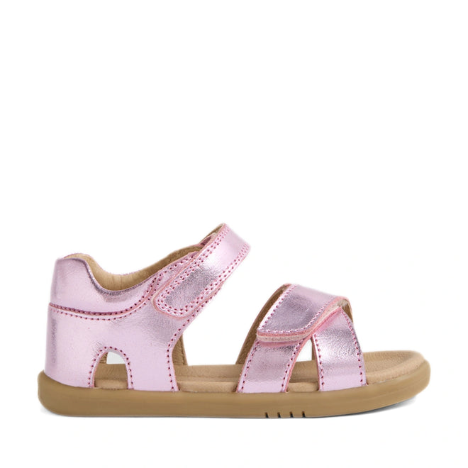 The Bobux IWalk Flora Toddlers Sandal in Pink Lemonade is a shiny metallic pink open-toe sandal for children, featuring two adjustable straps and a tan rubber sole. Shown on a white background, these breathable leather sandals offer toddlers both comfort and style.