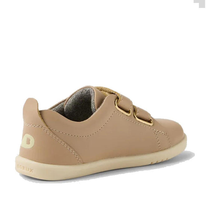 The Bobux IW Iwalk Grass Court Leather Sneaker in Warm Taupe is a light brown toddler shoe with a premium leather upper, two Velcro straps, beige sole, and visible stitching—shown from back and side on white. Perfect for street-styled collections., 9420074803368, 9420074803375, 9420074803382, 9420074803399, 9420074803405