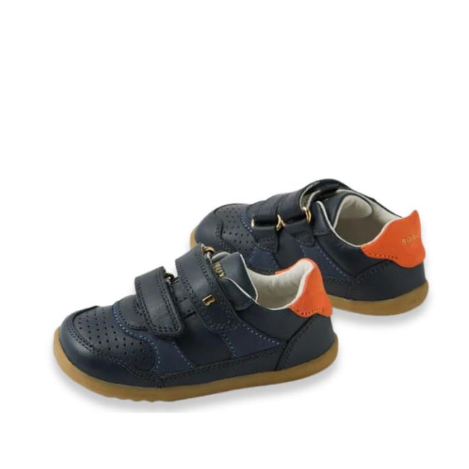 The Bobux IW Iwalk Hunter Leather Sneaker in navy for kids features tan soles, orange heel accents, perforated toe detailing, and two adjustable velcro straps, crafted from Quickdry leather and shown against a white background., 9420074834096, 9420074834102, 9420074834119, 9420074834126