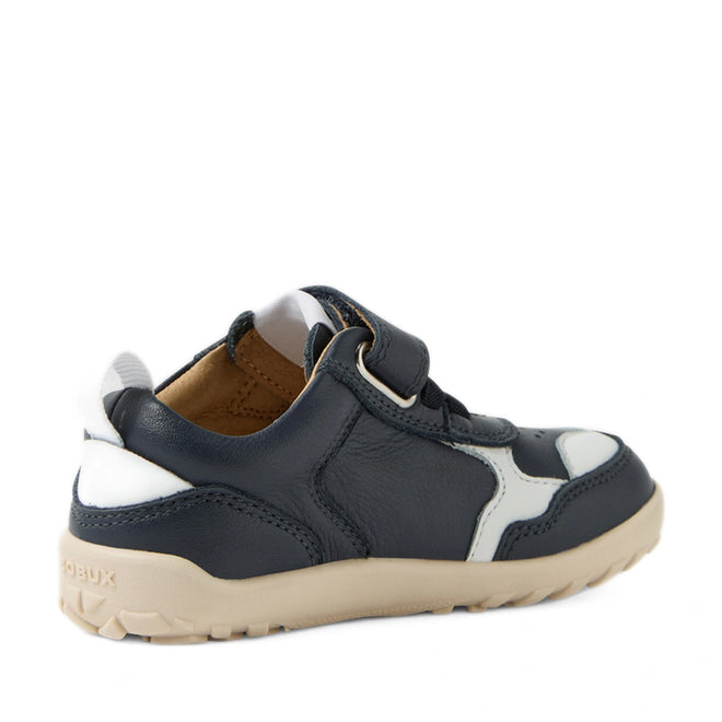 The Bobux IW Iwalk Neo Toddlers Leather Sneaker Navy Barefoot features premium navy blue and white leather with a beige sole, a Velcro strap, and a zero drop design to support natural foot development. Displayed at an angle from the back left side., 9420074854759, 9420074854766, 9420074854773, 9420074854780