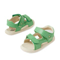A pair of Bobux IWalk Strand Sandal Retro Green Open Toe sandals for toddlers, featuring small green leather uppers, adjustable Velcro straps, and beige soles, displayed from two angles on a white background.