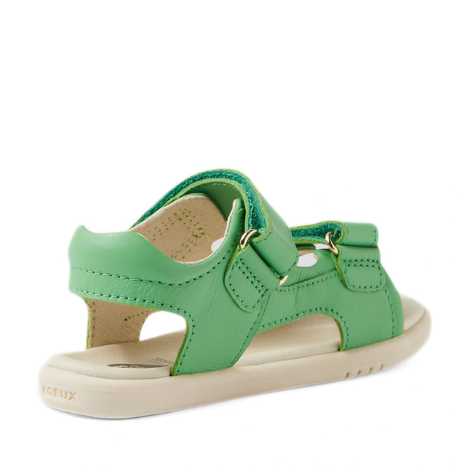 The Bobux IWalk Strand Sandal in Retro Green is shown angled from the back side, featuring an open heel and toe, gold buckles, and a beige sole. Made from washable leather with adjustable straps, these sandals are perfect for active toddlers.