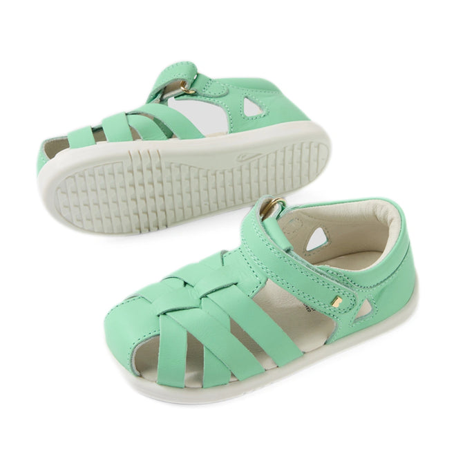 A pair of mint green, strappy closed-toe sandals for children—identified as the Bobux Iwalk IW Tropicana II Jelly Mint Green Leather Sandal—are displayed on a white background. One sandal stands upright while the other rests on its side to reveal the textured sole, showcasing these stylish and comfortable leather sandals that are ideal for little feet on the go., 9420074810038, 9420074810045, 9420074810052, 9420074810069, 9420074810076