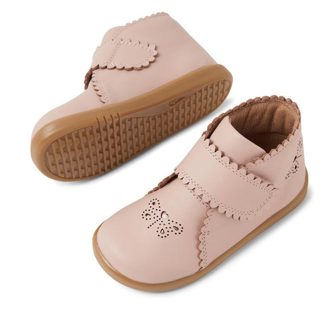 Two Bobux IW Iwalk Willow Leather Boot Cameo Rose Pink toddler shoes with brown rubber soles, scalloped edges, and a perforated butterfly on the toe. One shoe stands upright while the other shows its textured sole., 9420068545120, 9420068545137, 9420068545144, 9420068545151
