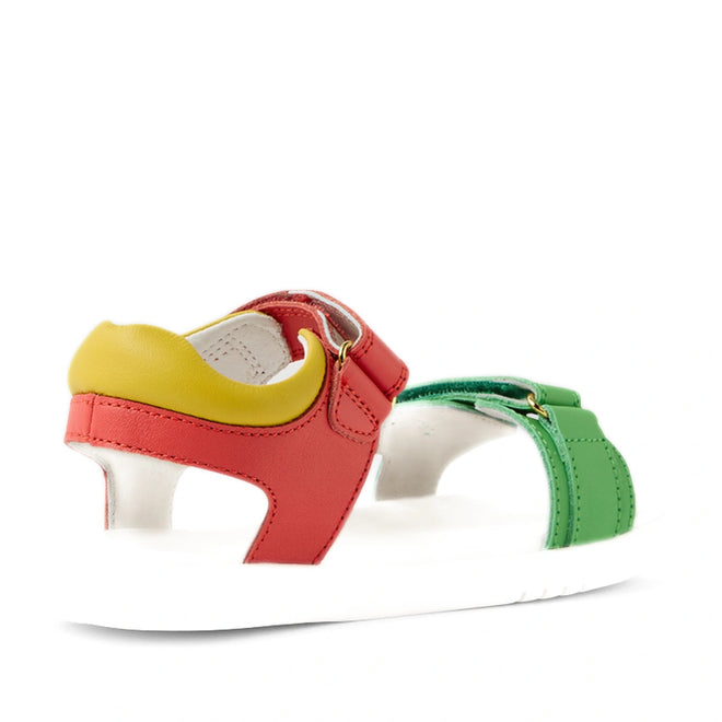 The Bobux KP Kids Plus Dune Leather Sandal Grenadine Red is a colorful kids’ leather sandal with a white sole, featuring red, green, and yellow leather straps with adjustable closures for a secure fit. The sandals are shown from the side and slightly behind on a white background., 9420074855688, 9420074855695, 9420074855701, 9420074855718