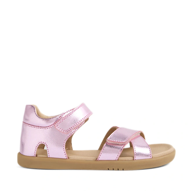 Introducing the Bobux KP Kids Plus Flora Leather Sandal in Pink Lemonade—a pair of metallic pink sandals featuring adjustable Velcro straps and a tan rubber sole, specially crafted for children’s comfort and style.