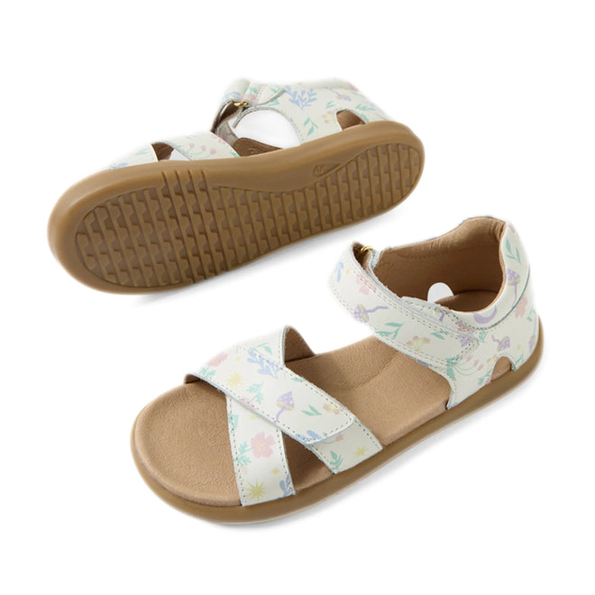 The Bobux KP Kids Plus Flora Leather Sandal in White Floral is an adjustable kids sandal featuring tan soles and white straps adorned with a pastel nature print of leaves and flowers. One sandal is displayed from the side, while the other is shown from the bottom.