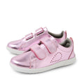 Bobux KP Kids Plus Grass Court 2 II Leather Sneaker in Pink Metallic features shiny pink leather, two velcro straps, white soles, and dotted side details. Designed with a wide fit inspired by the classic Bobux Grass Court style, these kids’ sneakers are shown placed side by side on a white background.