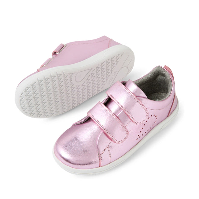 A pair of Bobux KP Kids Plus Grass Court 2 II Leather Sneakers in Pink Metallic, featuring two velcro straps, small side perforations, and white soles. Inspired by the original Grass Court design, these wide-fit leather shoes provide extra comfort for kids. One sneaker is shown upright while the other displays its textured grip sole.