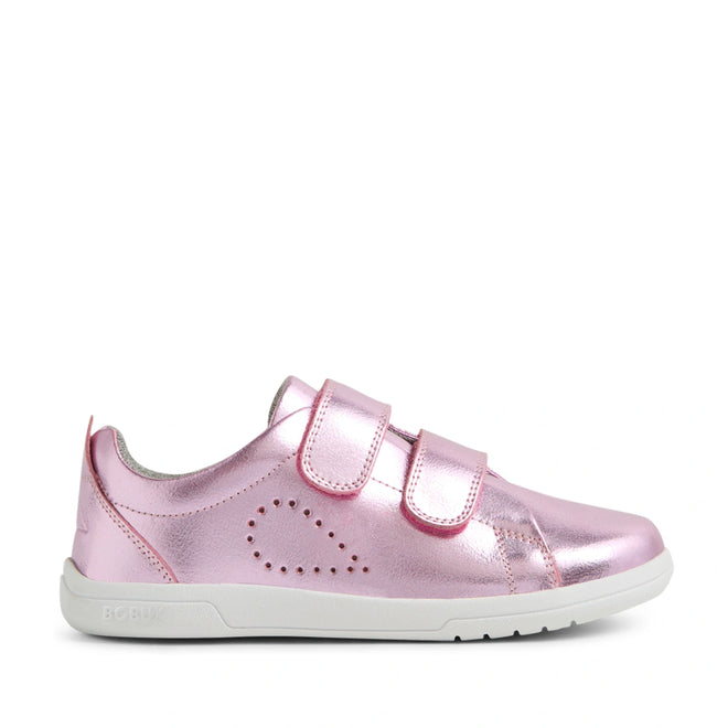 The Bobux KP Kids Plus Grass Court 2 II Leather Sneaker in Pink Metallic is a shiny pink leather sneaker for kids featuring two velcro straps, a white sole, and small perforations on the side forming a dotted heart shape. Designed in a wide fit for extra comfort, this style draws inspiration from the classic Bobux Grass Court collection.